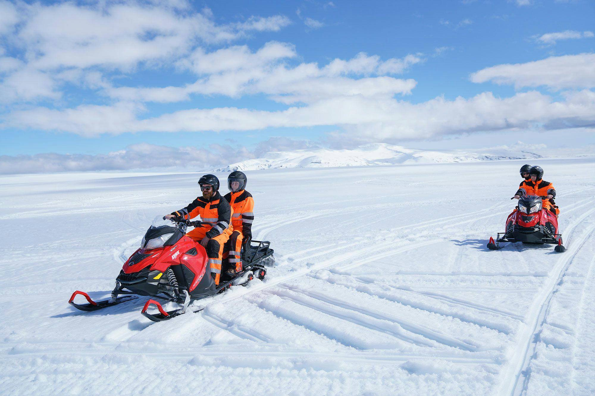 couples riding snowmobiles on langjökull glacier