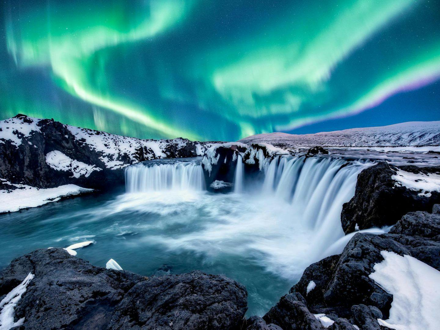 northern lights over waterfall in Iceland